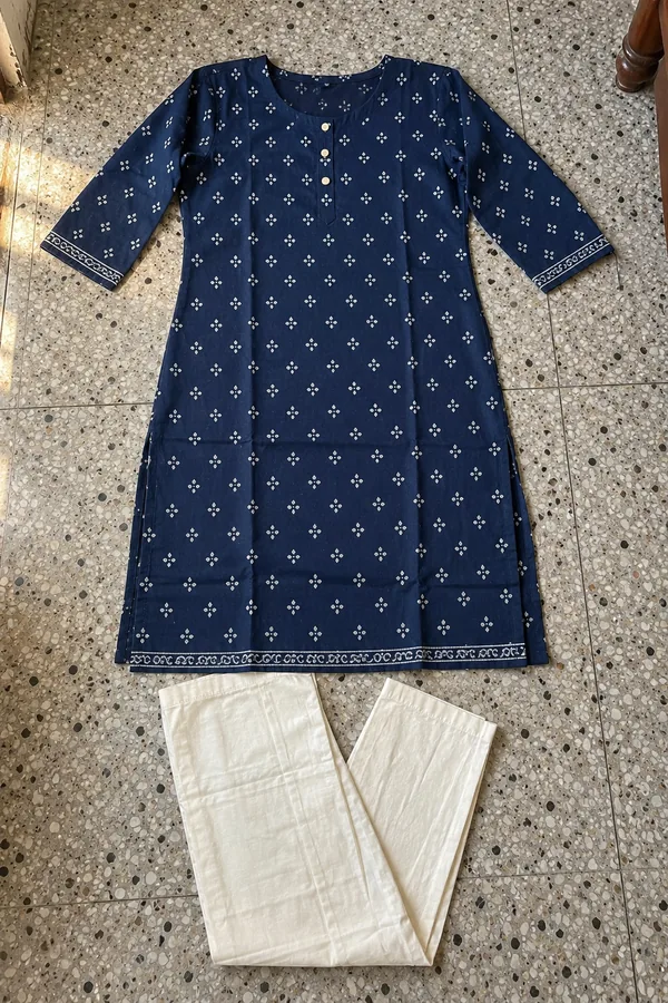 Indigo cotton kurta with small off-white block-printed motifs and plain off-white pants, laid flat on a terrazzo floor in daylight.