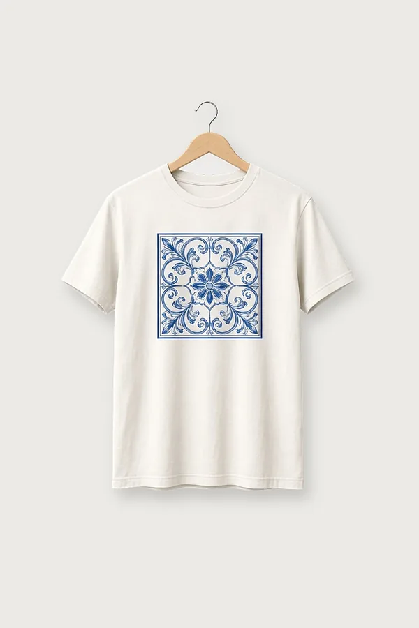 Off-white cotton T-shirt with a square cobalt-blue ornamental tile print, photographed on a wooden hanger against a plain light-grey background.